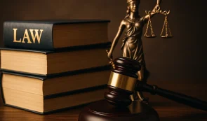 Law books, in a courtroom next to a statue and a gavel