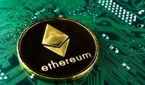 A physical Ethereum cryptocurrency token resting on a green printed circuit board.