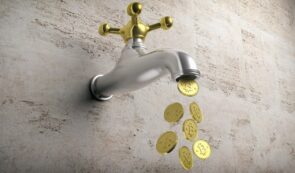 A 3D render of a metallic water tap mounted on a stone wall, dripping shiny gold Bitcoin coins instead of water drops.