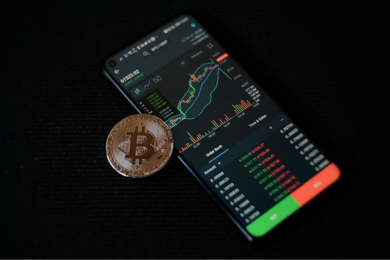 Mobile Phone screen showing charts with green and red and bitcoin token,