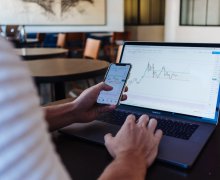 investor photo with laptop and mobile phone, looking at charts