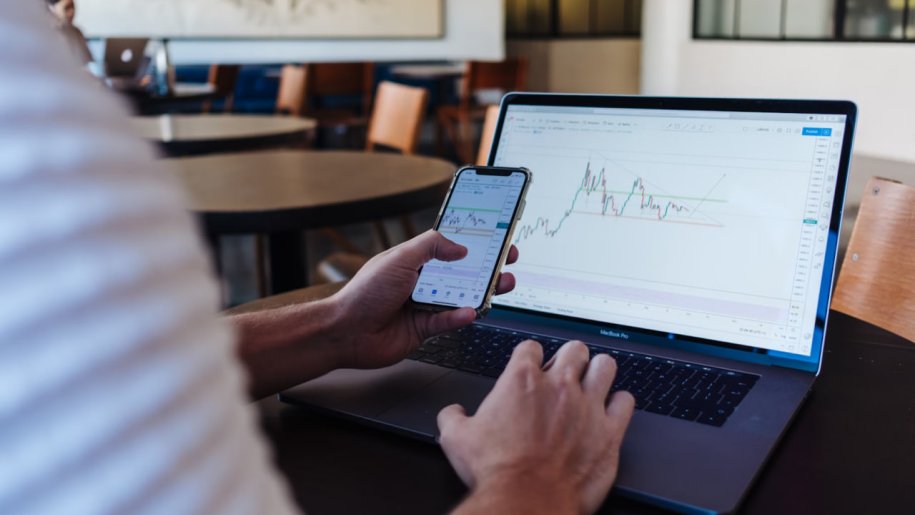 investor photo with laptop and mobile phone, looking at charts