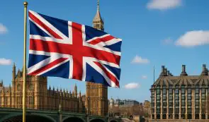 Union Jack flag waving proudly with the Houses of Parliament and Big Ben in the background.