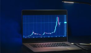 Laptop displaying a cryptocurrency price chart on a dark screen.