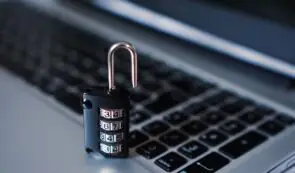 Open combination padlock resting on a laptop keyboard.