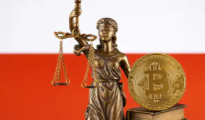 Statue of Lady Justice holding scales next to a physical Bitcoin coin resting on top of a book against the Polish national flag background, titled poland-crypto-law-3295.jpg.