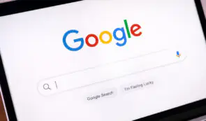Laptop screen displaying the Google Search homepage interface with the iconic colorful logo and search bar.