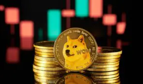 A physical Dogecoin (DOGE) gold token resting in front of a stack of coins against a backdrop of glowing red and green candlestick charts.