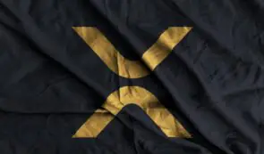 A gold XRP logo emblazoned on a dark, textured fabric flag.