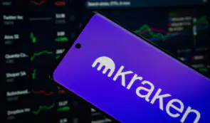 Kraken logo on smartphone screen, crypto market cap table in the background