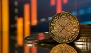 Physical XRP tokens resting on a reflective surface against a blurred background of orange and red financial market bars.