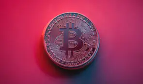 Bitcoin token on a red background signifying a price drop