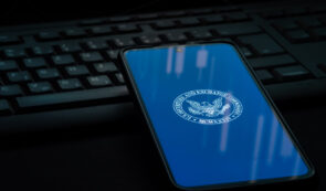 Smartphone displaying the U.S. Securities and Exchange Commission (SEC) seal on a blue screen, resting on a dark laptop keyboard