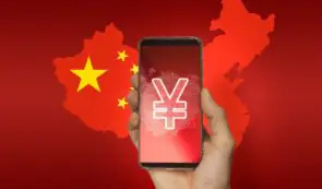 A hand holding a smartphone displaying a glowing digital Chinese Yuan currency symbol over a background map of China and its national flag.