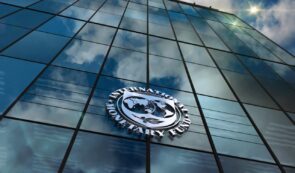 International Monetary Fund (IMF) logo mounted on the reflective glass facade of a modern corporate building.