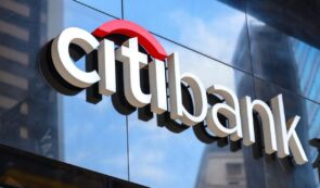 Citibank illuminated corporate logo and signage mounted on a glass exterior building facade.