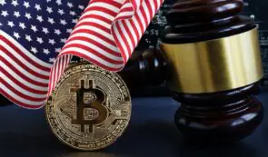 Physical Bitcoin coin positioned beside a wooden judge's gavel and draped with an American flag.