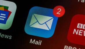 Close-up macro photograph of a smartphone screen displaying the Mail app icon with a red notification badge showing two unread messages.
