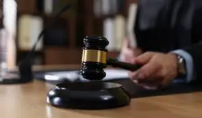 Close-up photograph of a judge's gavel striking the sounding block in a courtroom setting, symbolizing legal rulings and asset seizures.