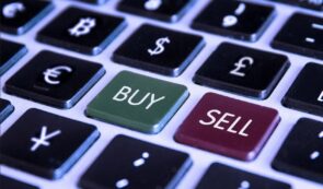 Extreme close-up of a computer keyboard featuring dedicated green BUY and red SELL keys surrounded by fiat currency symbols and Bitcoin
