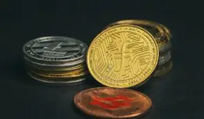 Physical cryptocurrency tokens including Filecoin, Litecoin, and Bitcoin arranged on a dark surface.