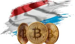 Three physical golden Bitcoin coins positioned in front of a stylized brushstroke graphic of the flag of Luxembourg.