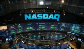 Alt: The illuminated Nasdaq stock exchange sign and electronic trading floor displays in New York.